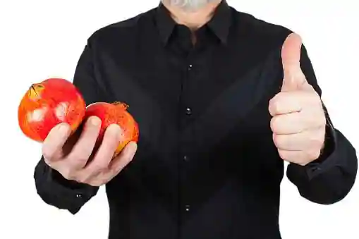 pomegranate in hands of a man with thumbs up